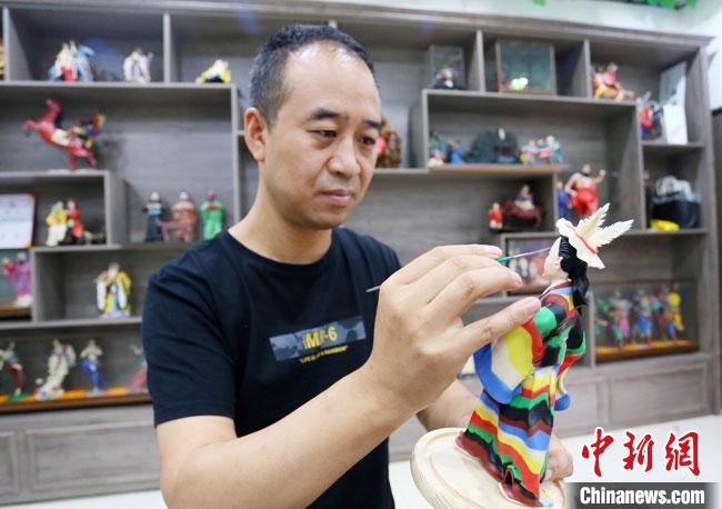 圖為安秋平正在創(chuàng)作代表隴南文縣民俗的《白馬人》作品。　高展 攝