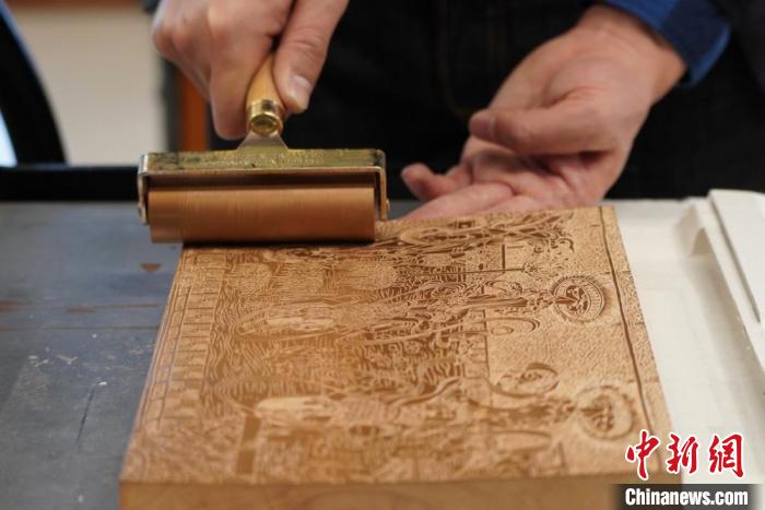 圖為徐晉林工作室工作人員正在給雕好壁畫的版面滾油墨。　九美旦增 　攝