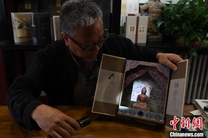 圖為讀者出版集團(tuán)讀者晉林工作室獨(dú)立出品人徐晉林，展示互動性強(qiáng)的敦煌題材手工書。(資料圖) 楊艷敏 攝