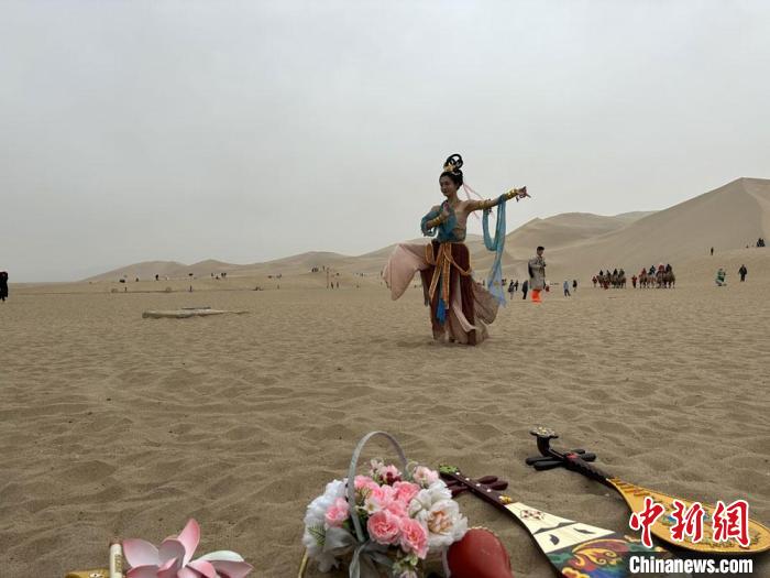 圖為2023年4月底，敦煌大漠“逐舞者”奧楠在鳴沙山月牙泉景區(qū)視頻直播敦煌舞?！●T志軍 攝